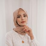 Studio shot of a beautiful woman wearing a hijab and white lace dress, exuding elegance and grace.